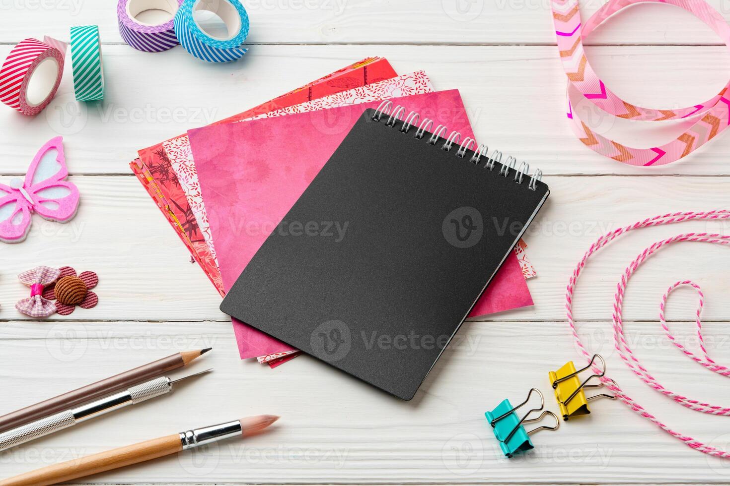 Crafting essentials on a workspace featuring a black notebook, colorful paper, and decorative supplies photo