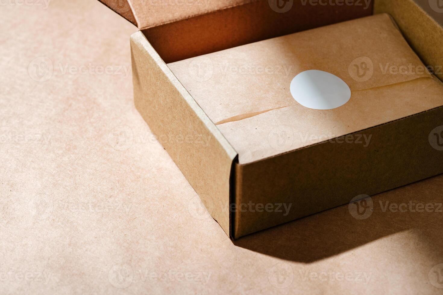 A sealed kraft box containing a wrapped item, positioned on a textured brown surface for an unboxing experience photo