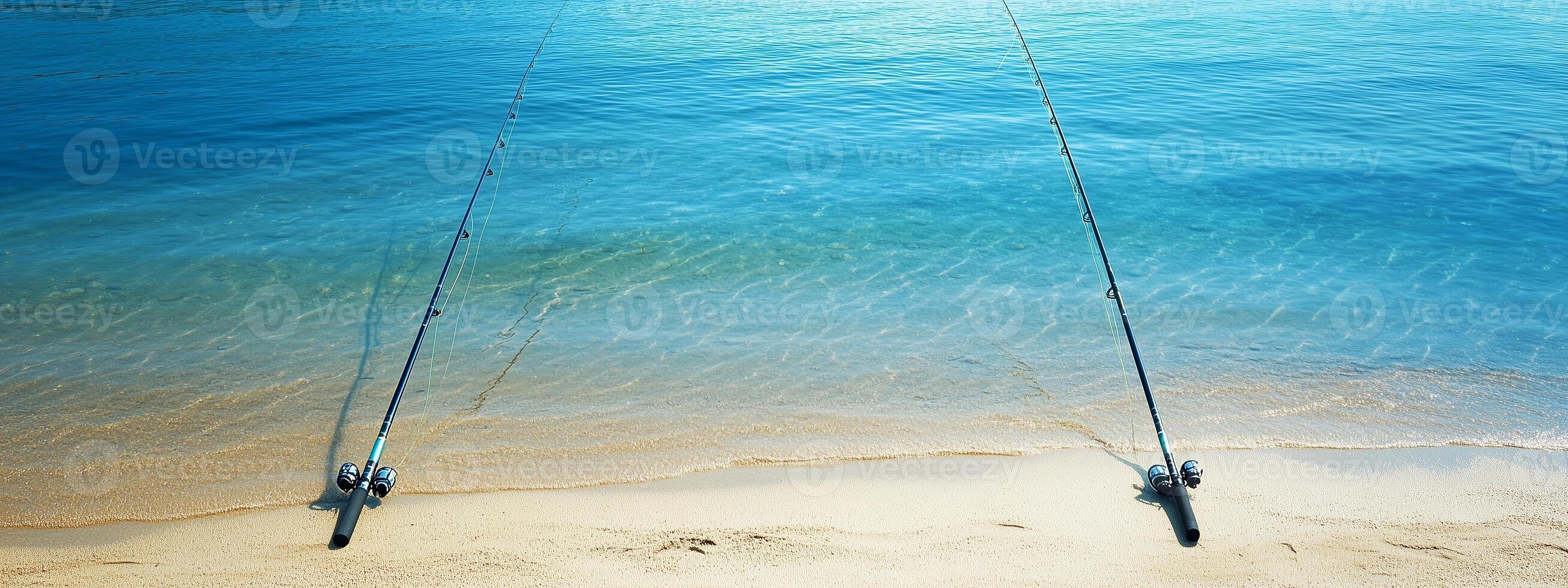 Two fishing rods set on the sandy beach by turquoise waters on a sunny day photo