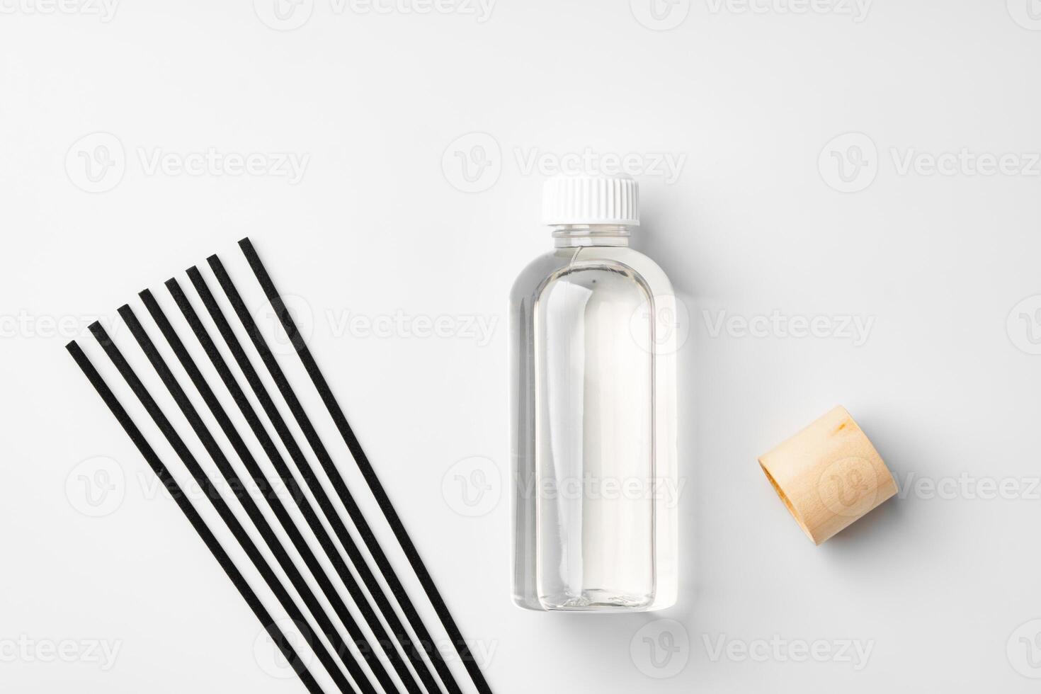 A minimalist display of essential oil and black diffuser sticks on a clean white background photo
