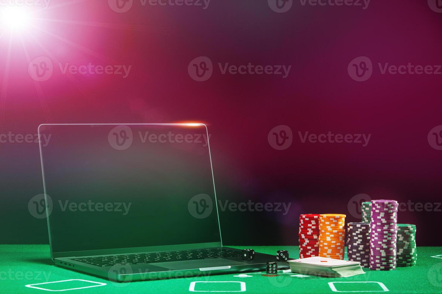 A laptop and poker chips arranged on a green felt table in an indoor gaming setup during a nighttime gambling session photo