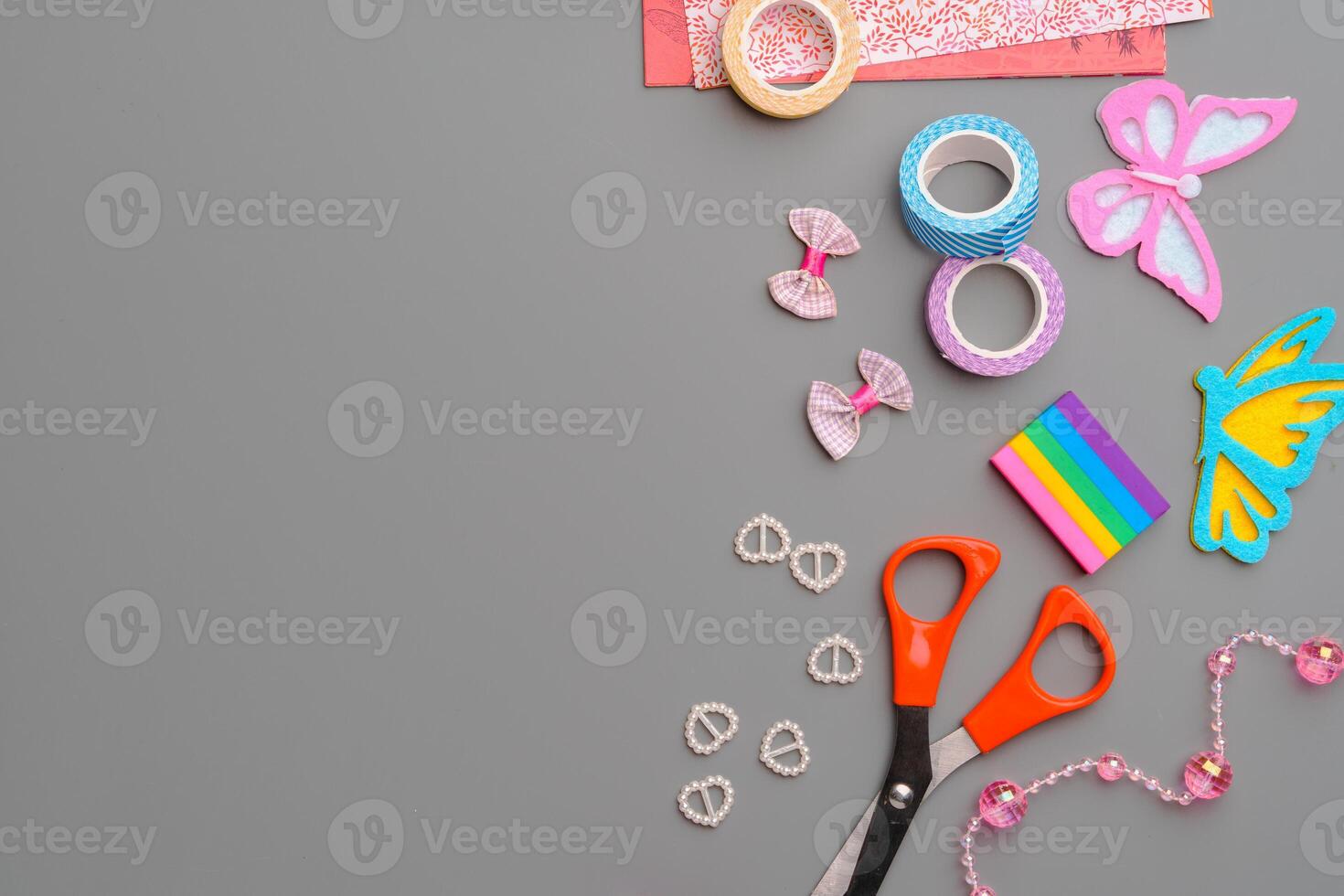 Crafting supplies arranged for a DIY project on a gray table with scissors, washi tape, and decorative items photo