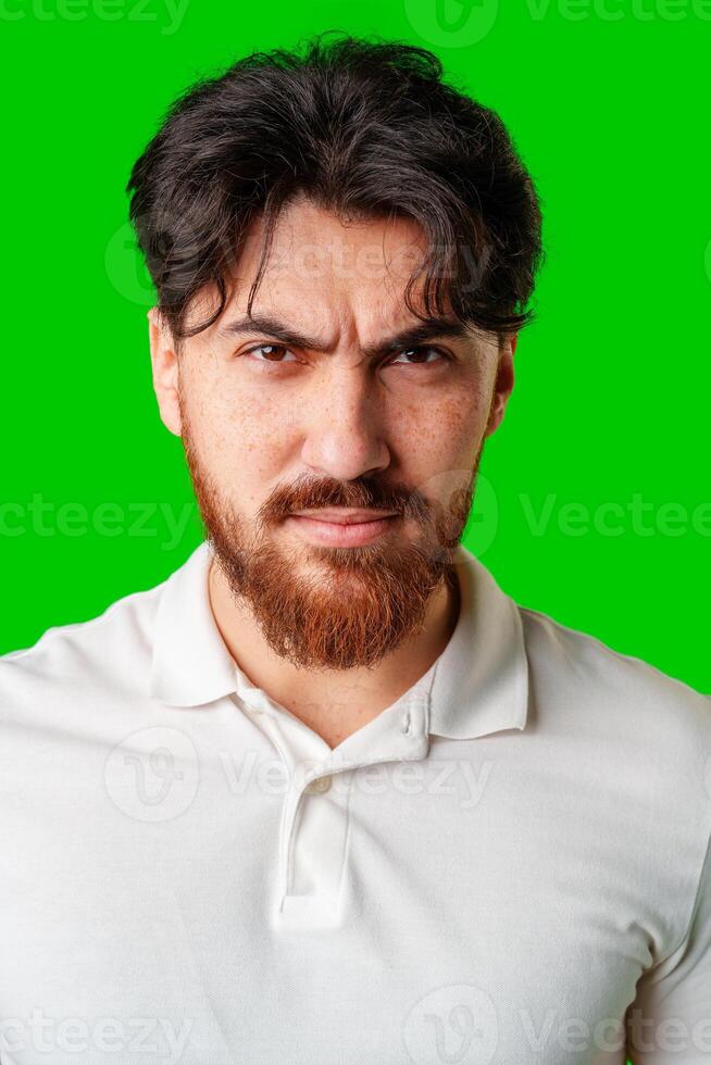 A young man with a beard showing a serious expression against a vibrant green background photo