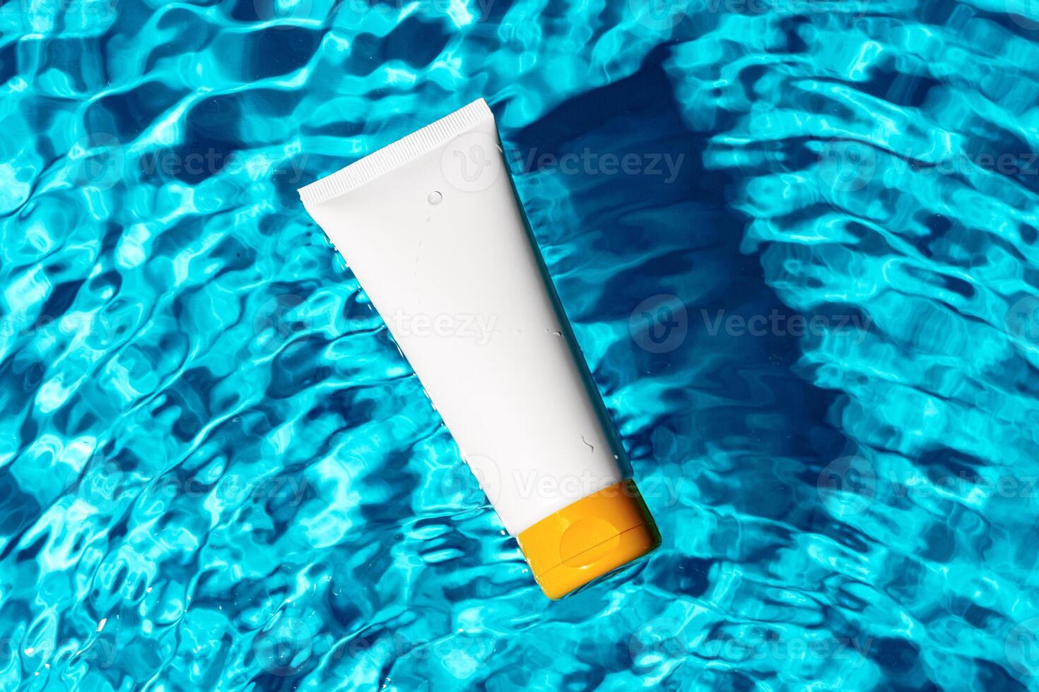 Sunscreen bottle floating in a clear blue swimming pool on a sunny day photo