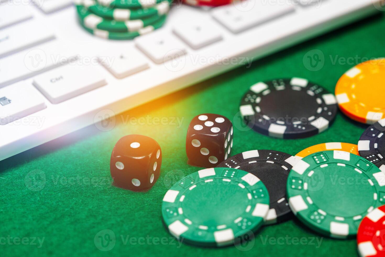 Chips and playing cards on a green felt surface near a computer keyboard during an online gaming session at home photo