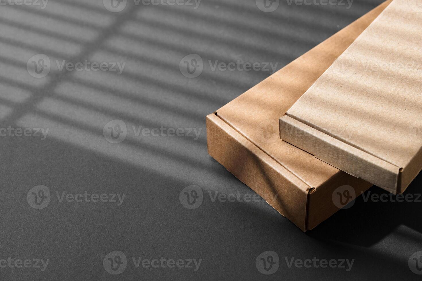 Various sizes of brown cardboard boxes arranged on a black surface with soft lighting effects during the day photo