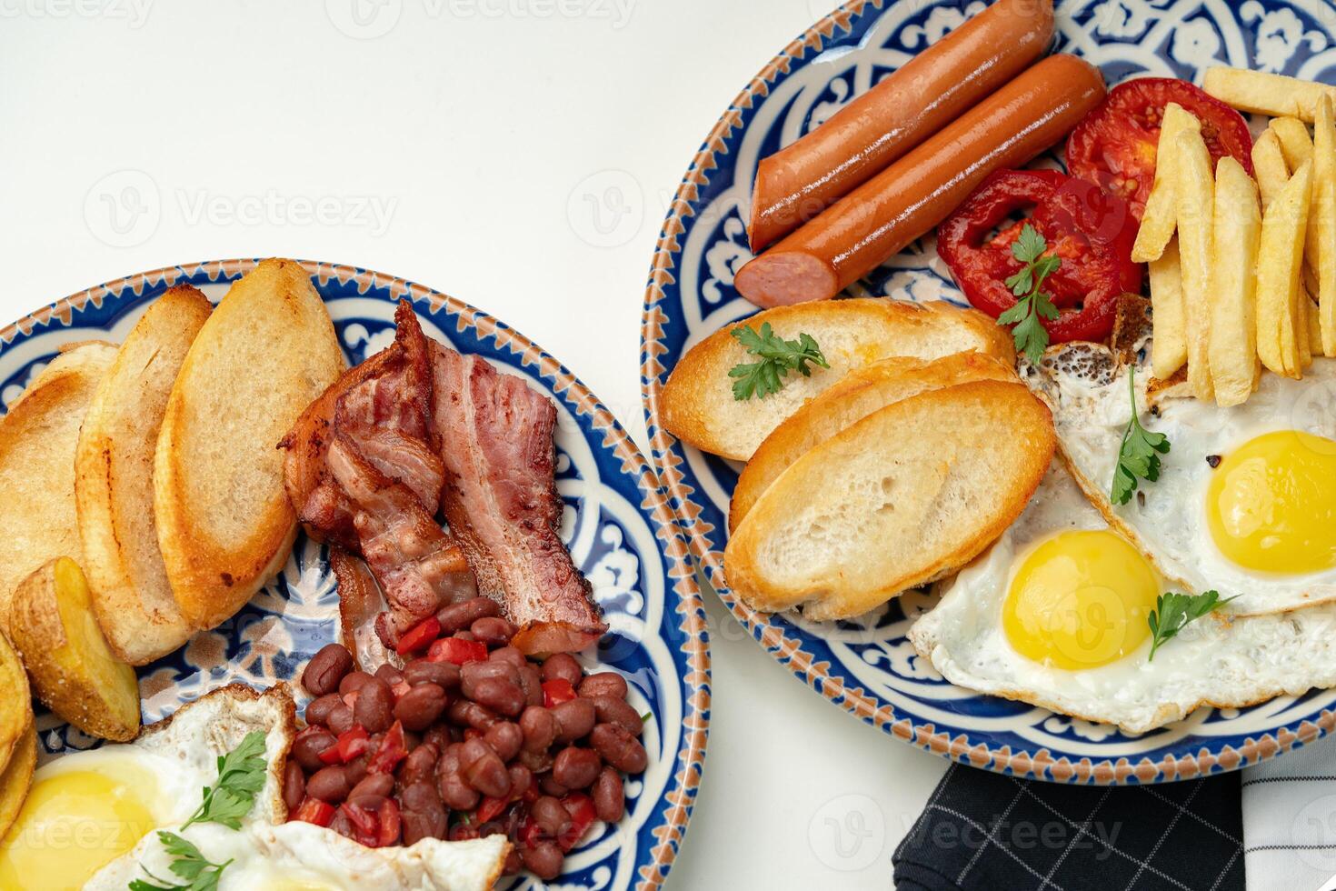 Two plates of a hearty breakfast served on decorative bowls photo