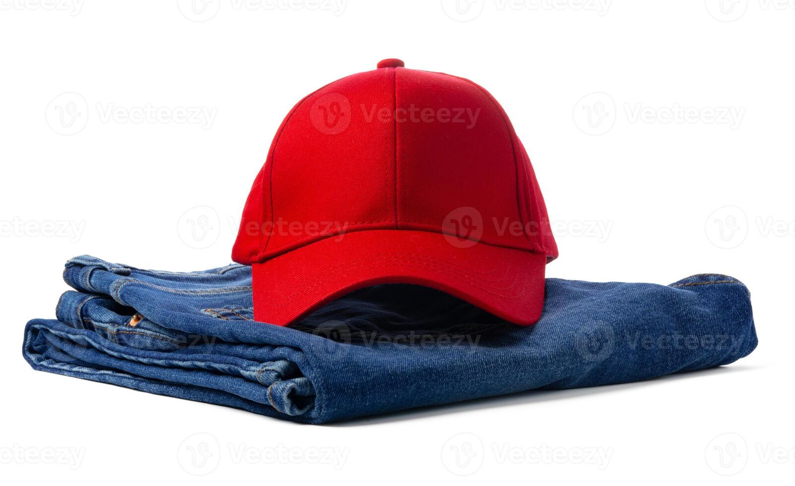 Red Baseball Cap Resting Atop Folded Blue Denim Jeans Against a White Background photo