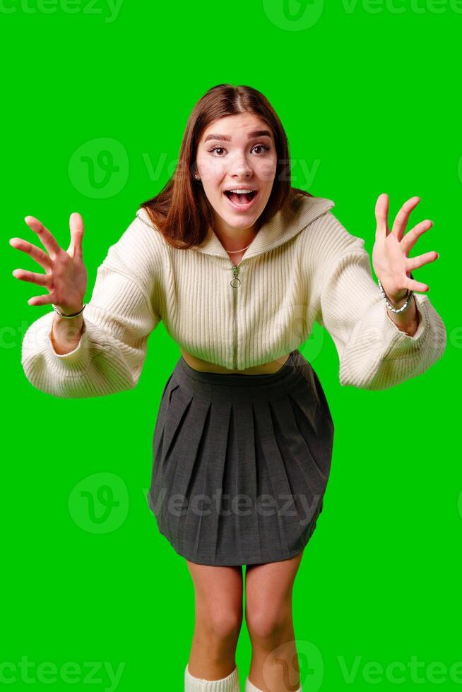 Young Woman Gesturing Excitement in Casual Attire Against Green Screen Backdrop photo