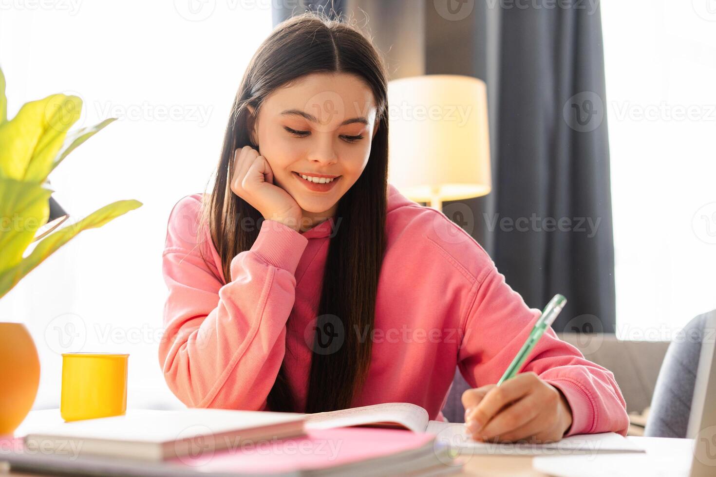 Young girl, teenager taking notes while studying at home photo
