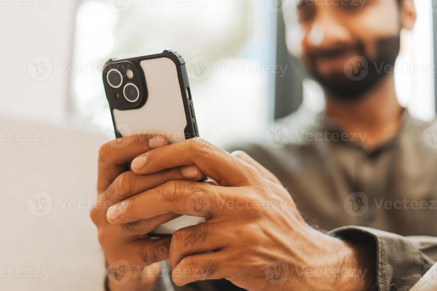 Smiling Indian man holding using smartphone browsing internet, selective focus, closeup on hands photo