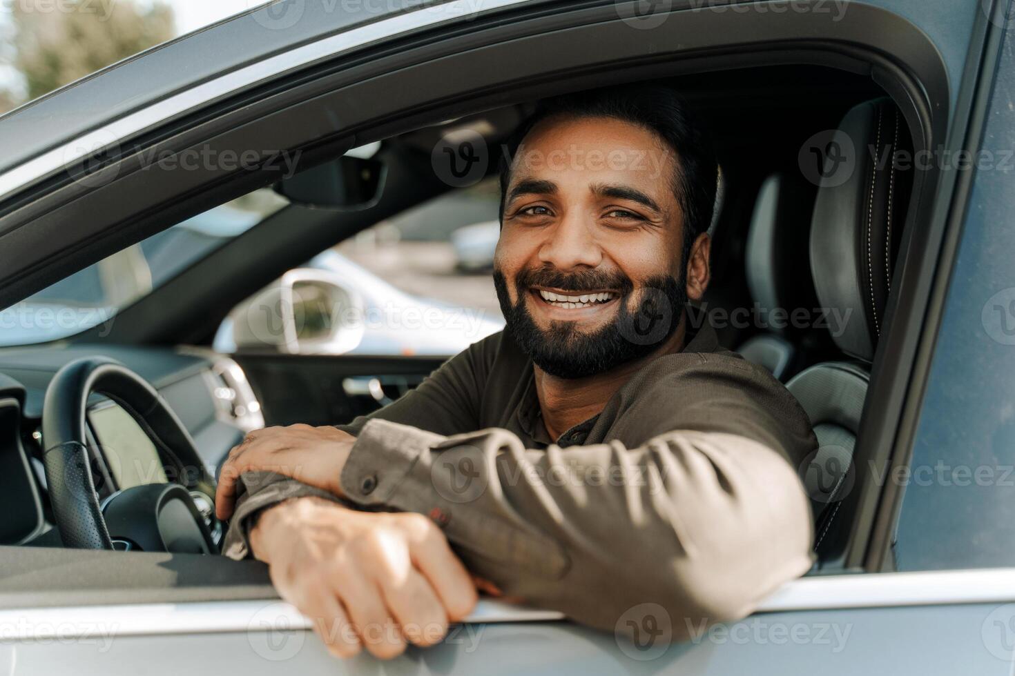 Happy Idian man smiling while sitting in car looking at camera photo