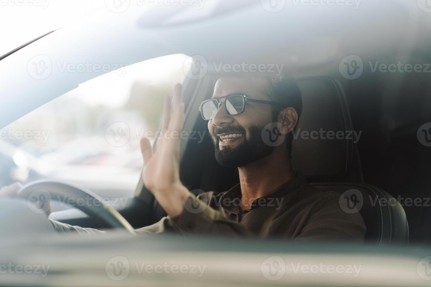Happy businessman waving while driving modern car photo