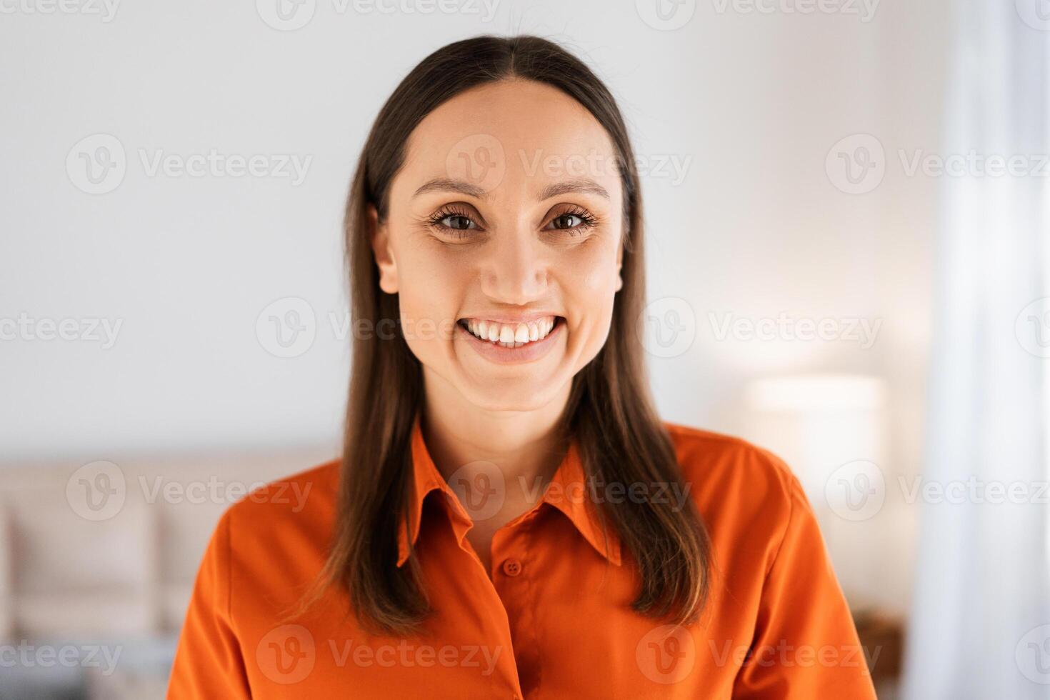 Beautiful smiling woman looking at camera while posing at home photo