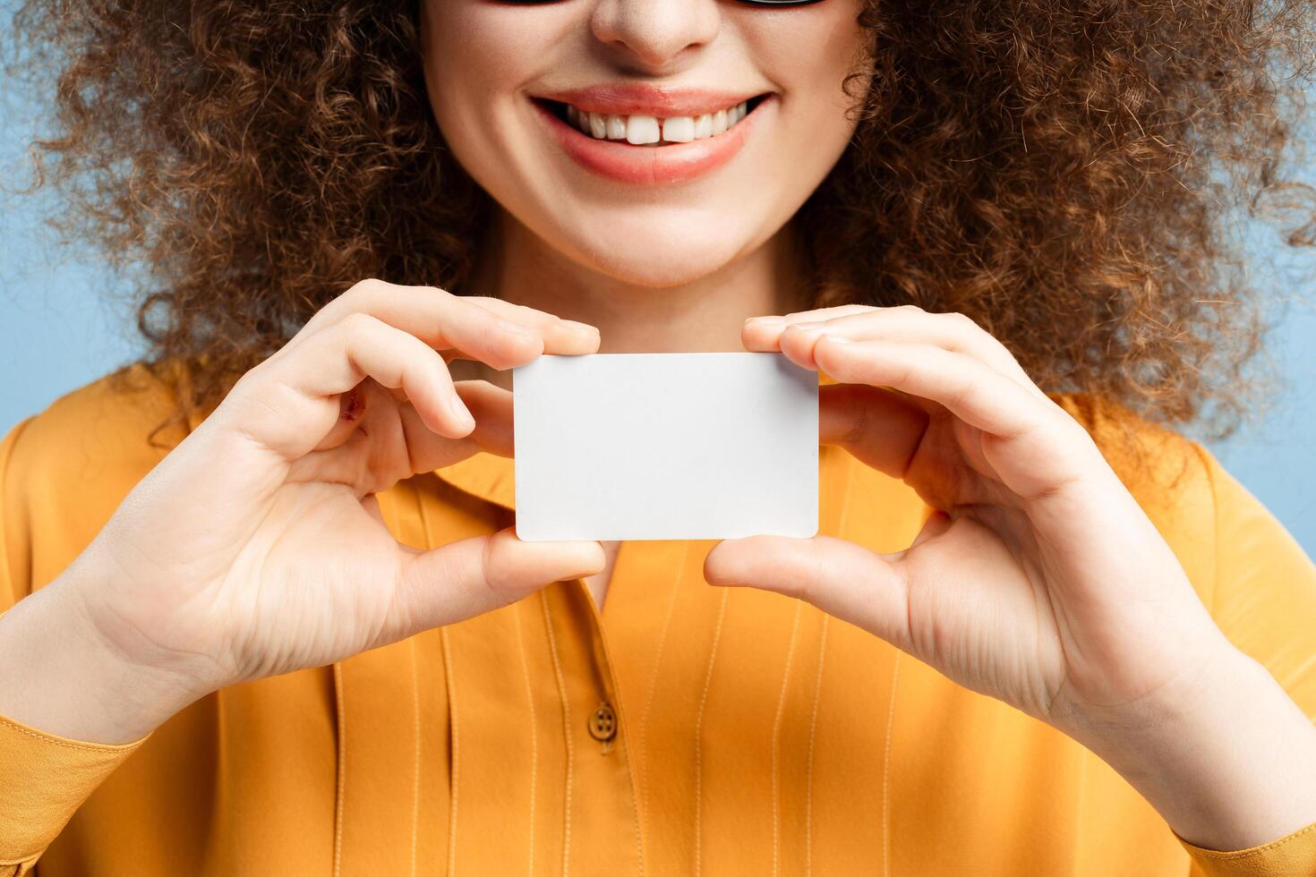 Smiling woman with curly hair businesswoman holding blank business card mockup photo