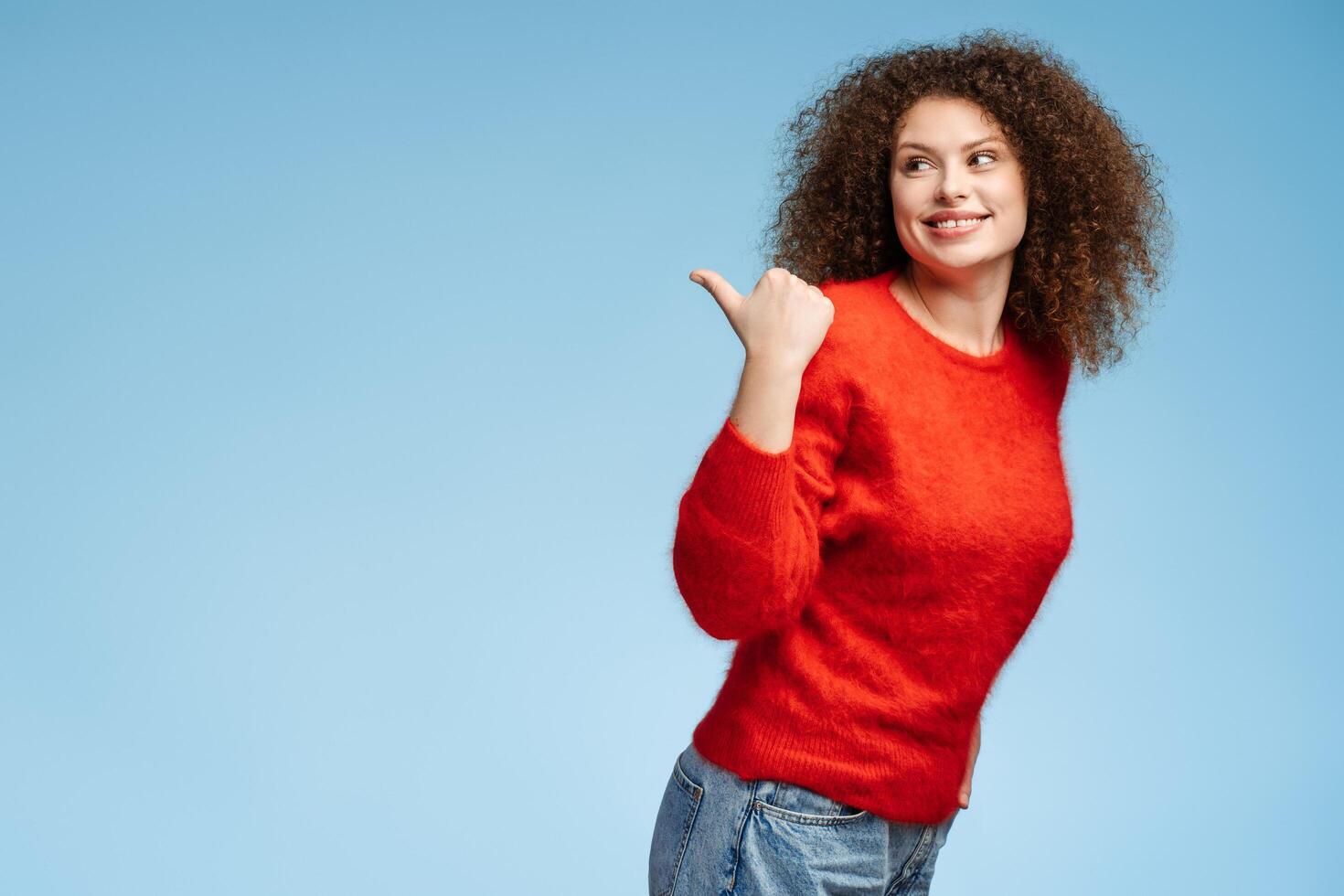 Attractive smiling woman wearing casual clothes pointing finger at copy space, looking away photo
