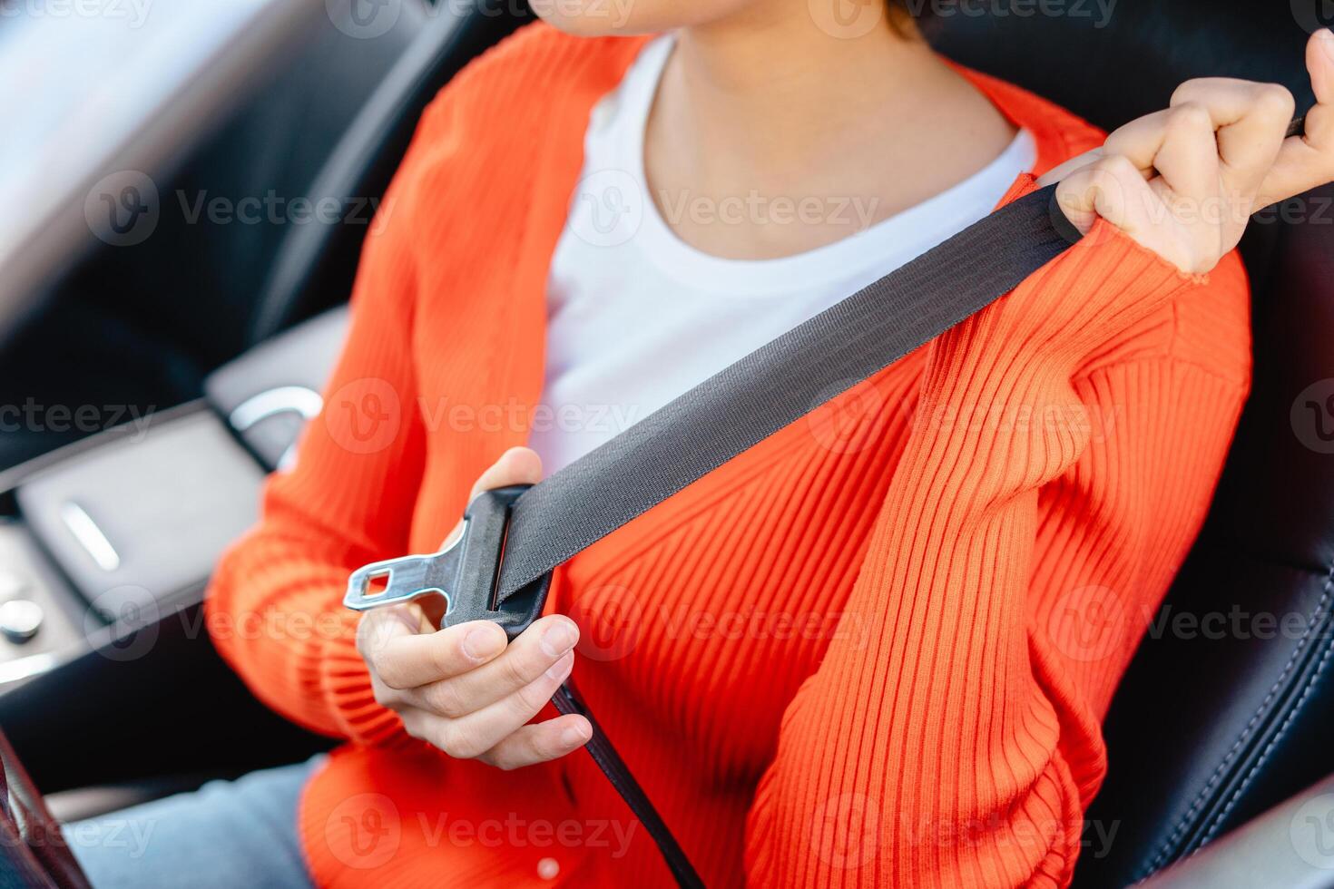 Young woman, driver fastens seat belt, sitting in car salon, selective focus on hands photo