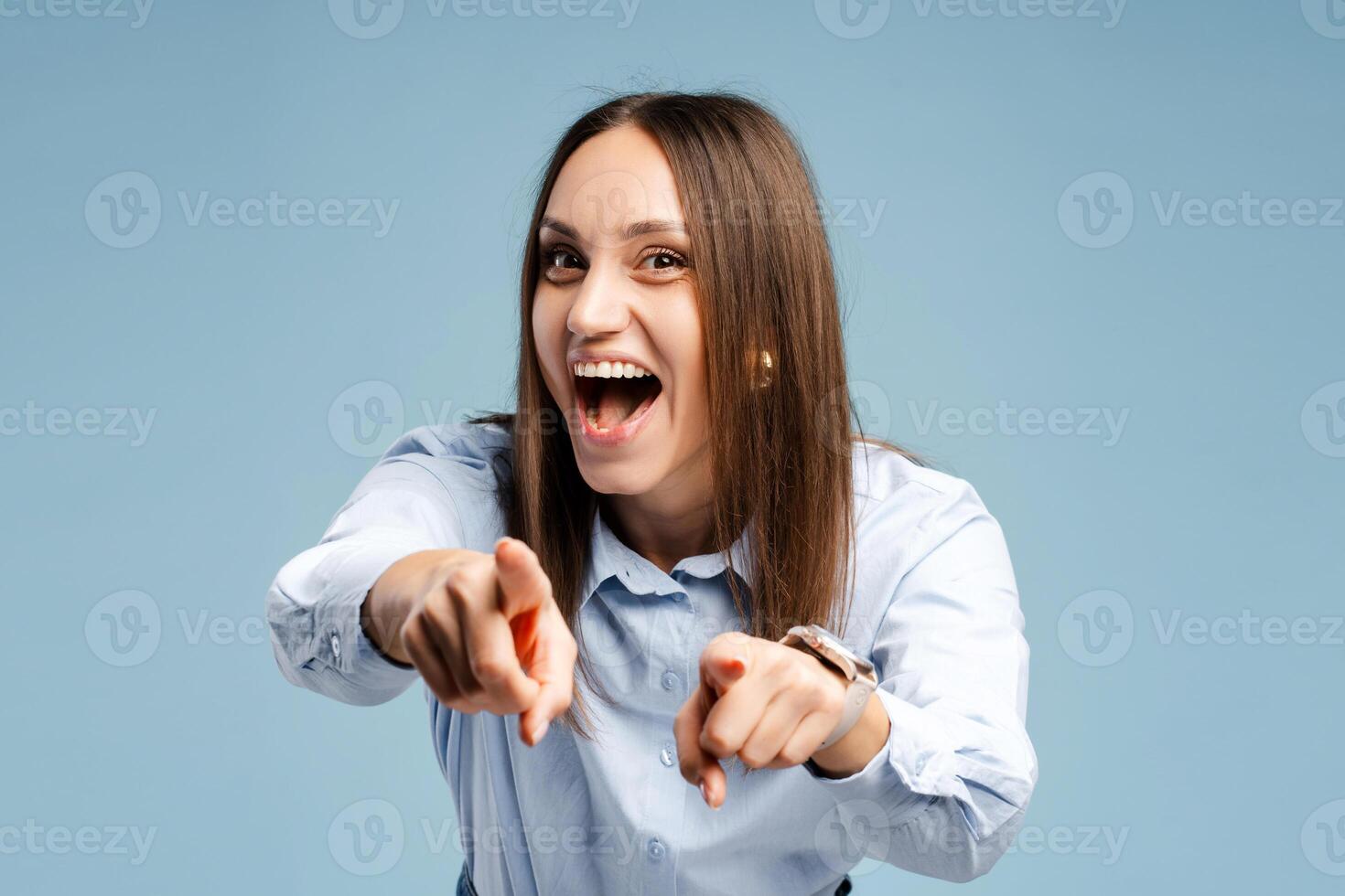 Positive cheerful young woman pointing at camera with index fingers, isolated on blue photo