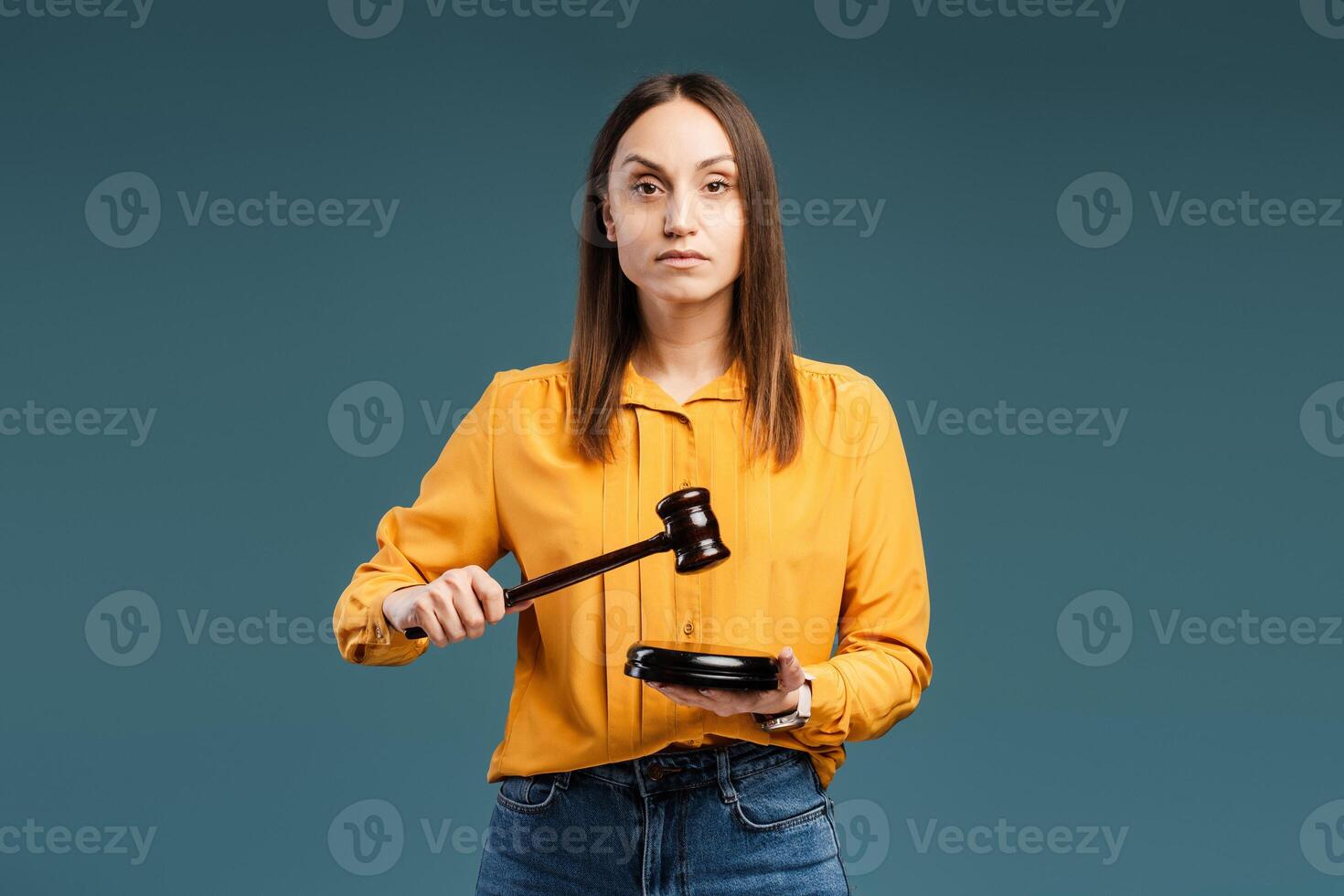 Portrait of calm young woman knocking a gavel posing in the studio, looking at camera, isolated photo