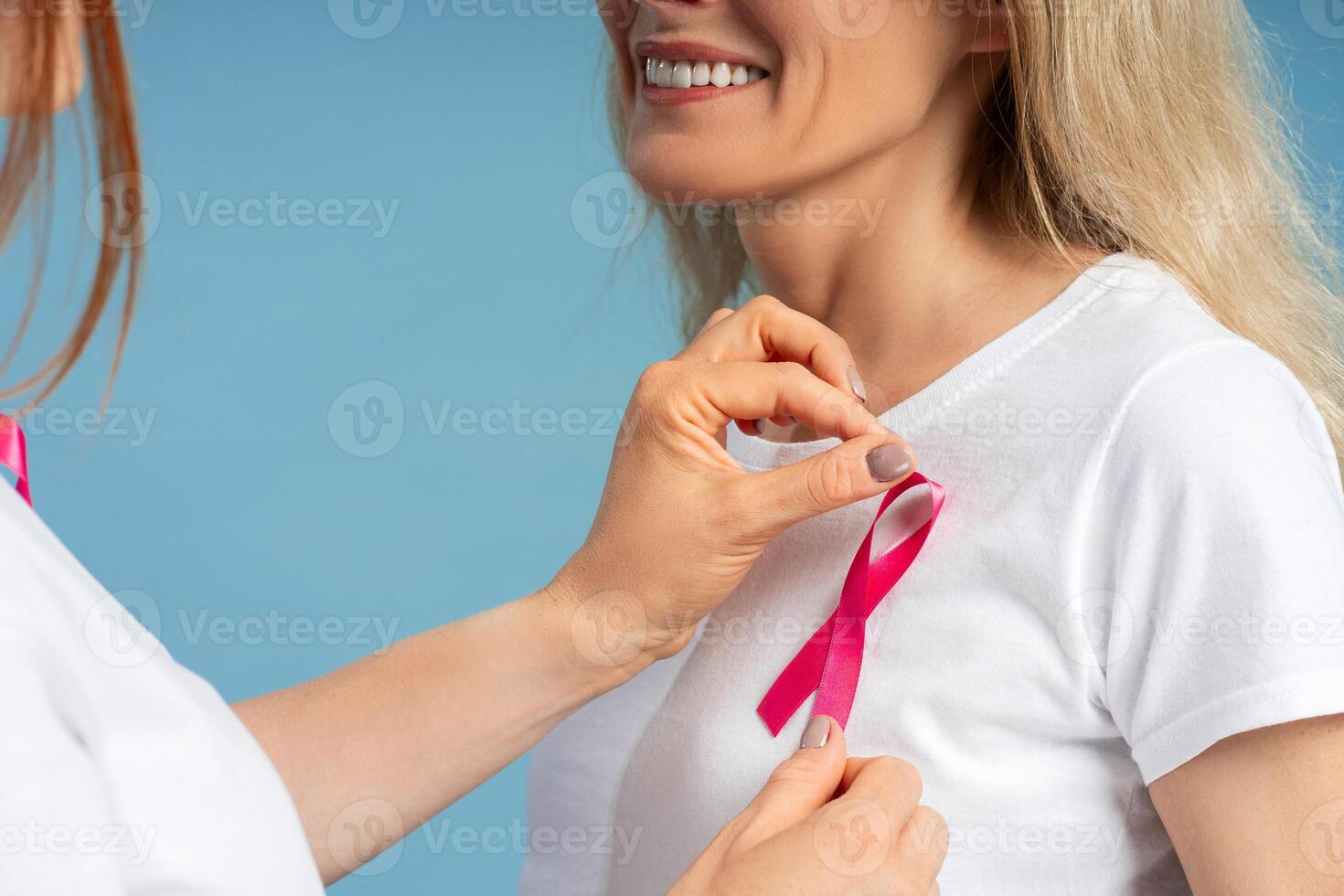 Doctor placing pink ribbon showing support for breast cancer awareness on patient photo