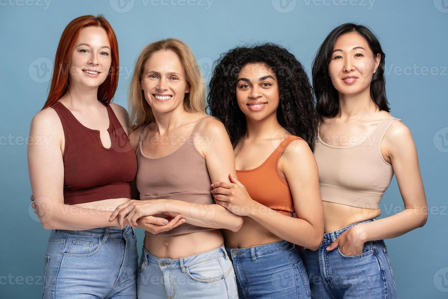 Diverse group for multinational smiling women wearing stylish top and tank top, hugging posing photo