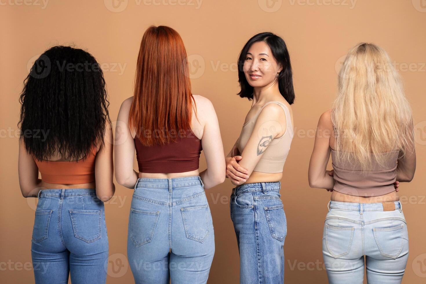 Group of women posing in denim, rear view, Asian woman looking at camera isolated on blue background photo