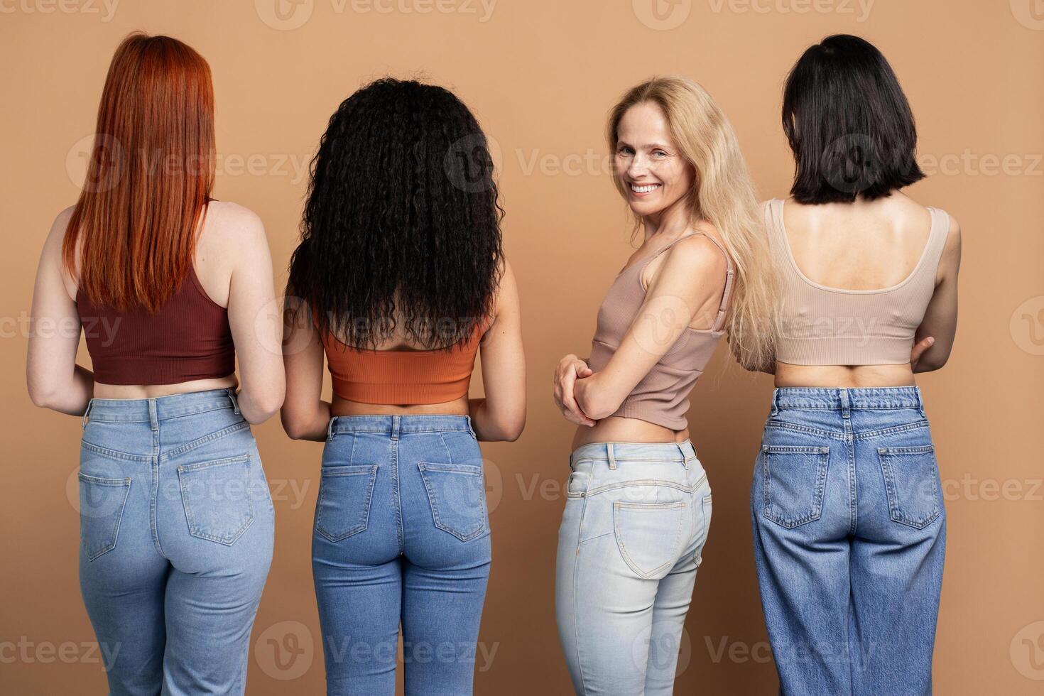 Diverse group of women posing in denim, rear view, woman with blonde hair looking at camera photo
