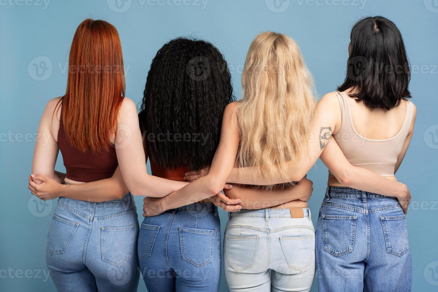 Rear view four diverse women standing posing on blue background photo