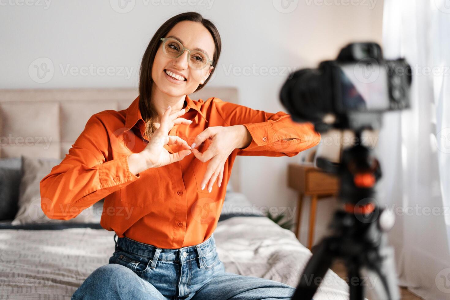 Cheerful caucasian woman talking and showing sign language while recording photo