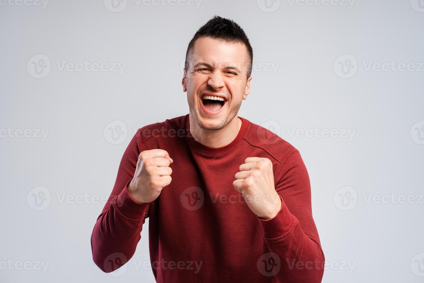 Closeup smiling young man fan looking at camera and clenching fists say yes photo