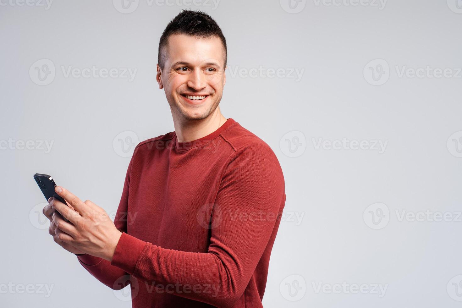 Smiling, attractive middle aged man wearing stylish red sweater, holding mobile phone photo
