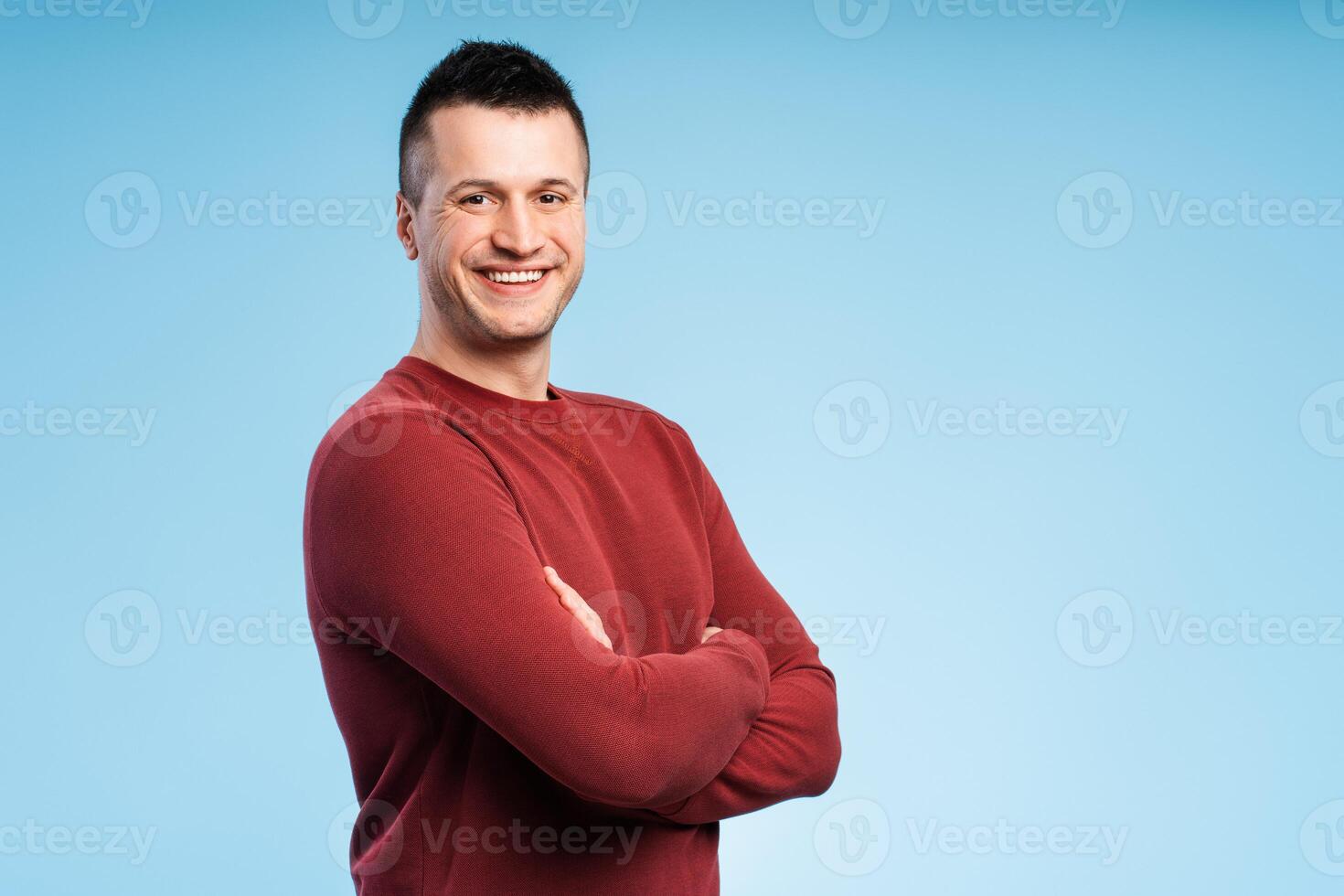Happy smiling man standing with arms crossed, isolated on blue background photo