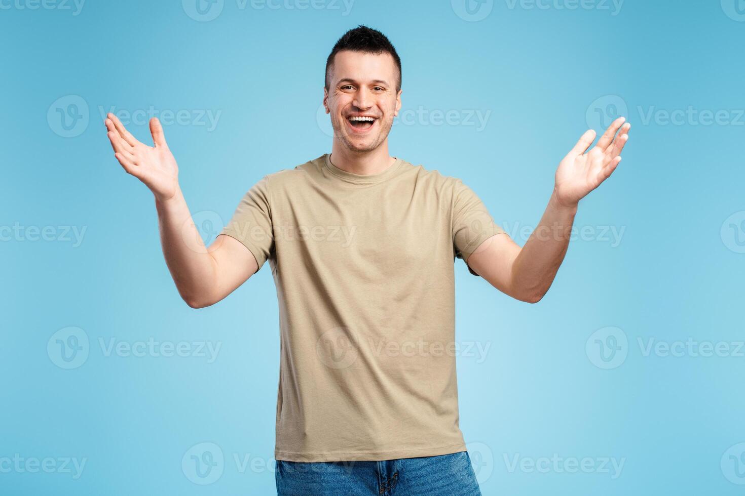 Smiling happy man in casual clothes rejoicing, glad to see, isolated on blue background photo