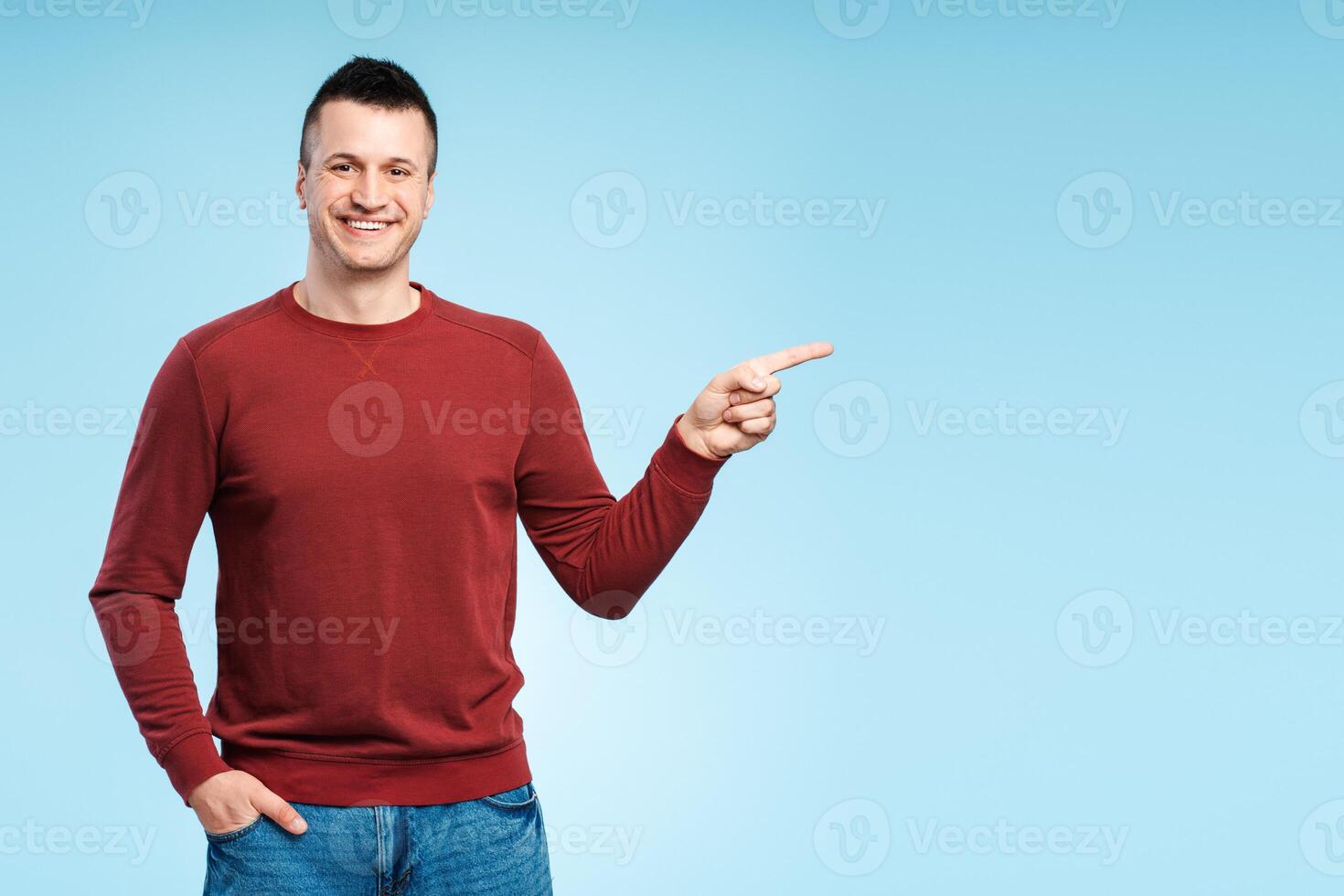 Happy smiling man in casual clothes pointing his finger at copy space for ad text photo