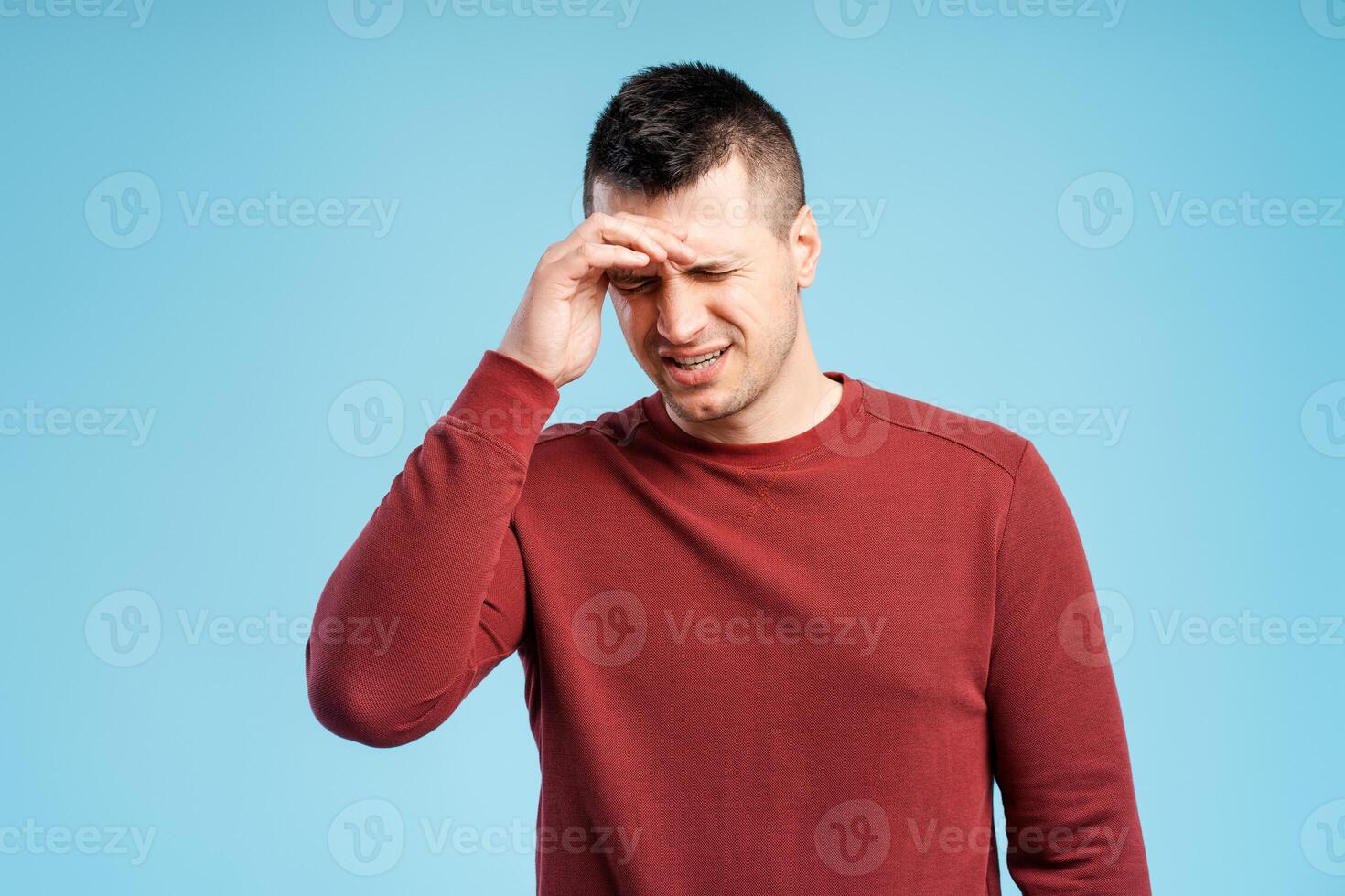 Middle aged man touching his forehead from pain having headache standing isolated on blue background photo
