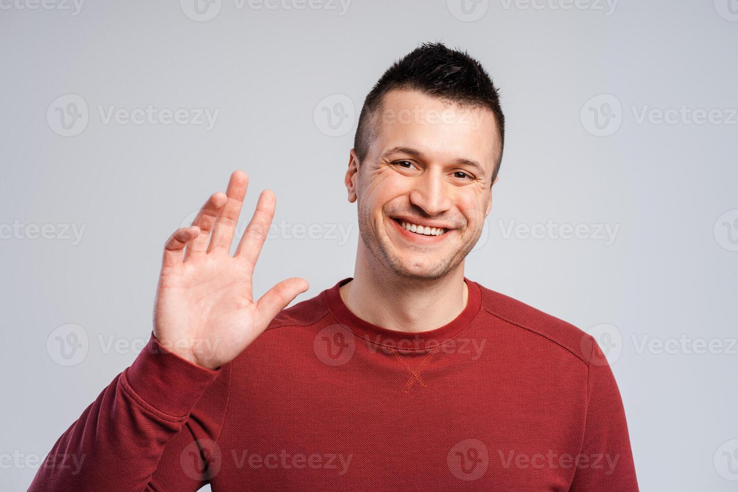 Handsome, attractive, smiling man waving hand, looking at camera, gesturing photo