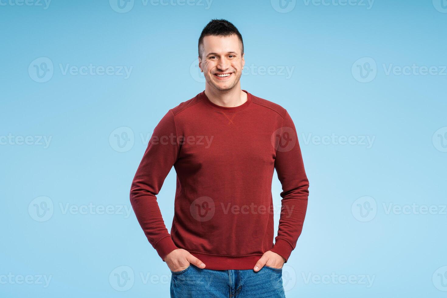 Smiling, middle aged man standing with hands in pockets, wearing casual red sweatshirt photo