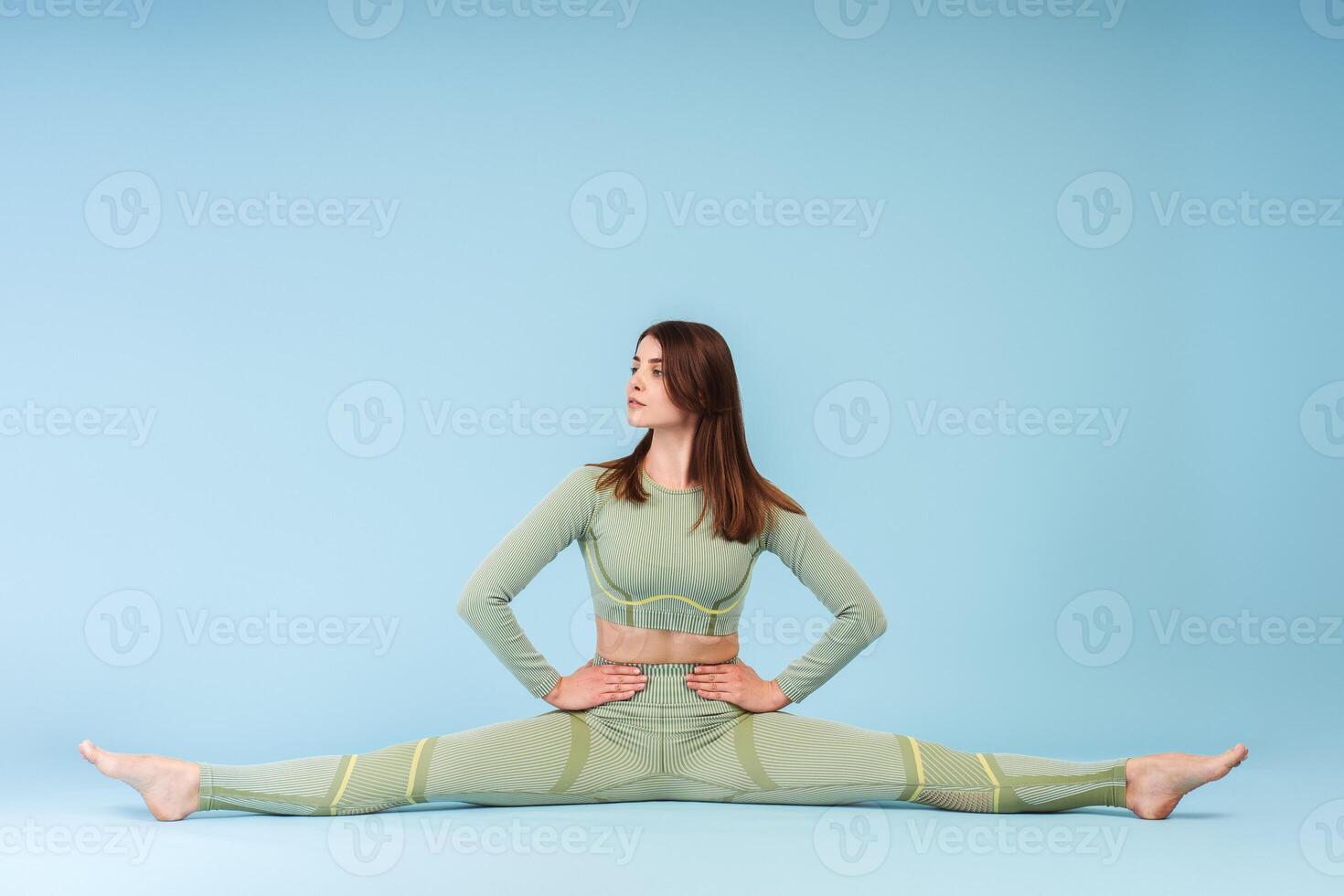 Serious woman wearing stylish sports uniform sitting on twine, training doing exercises looking away photo