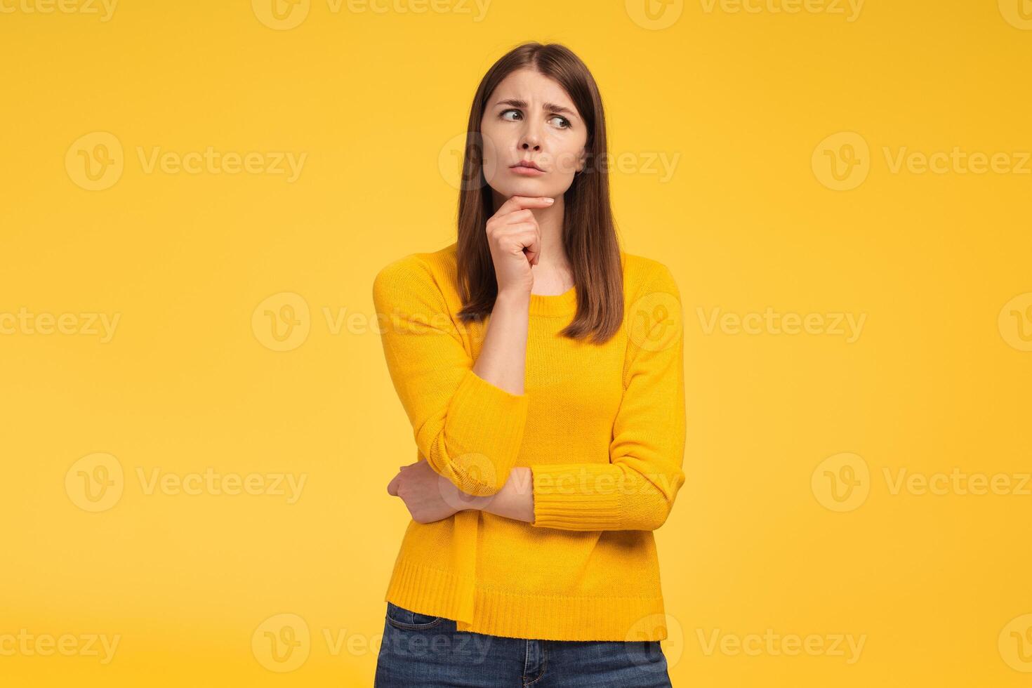 Serious middle aged woman looking away, choosing something, standing isolated on yellow background photo