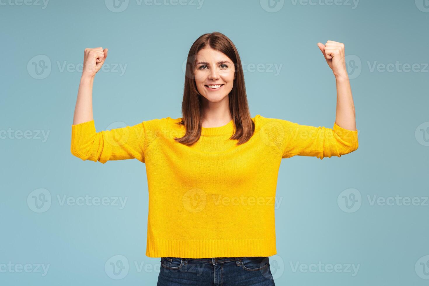 Cheerful, smiling, beautiful woman showing her strong arms, biceps, looking at camera photo