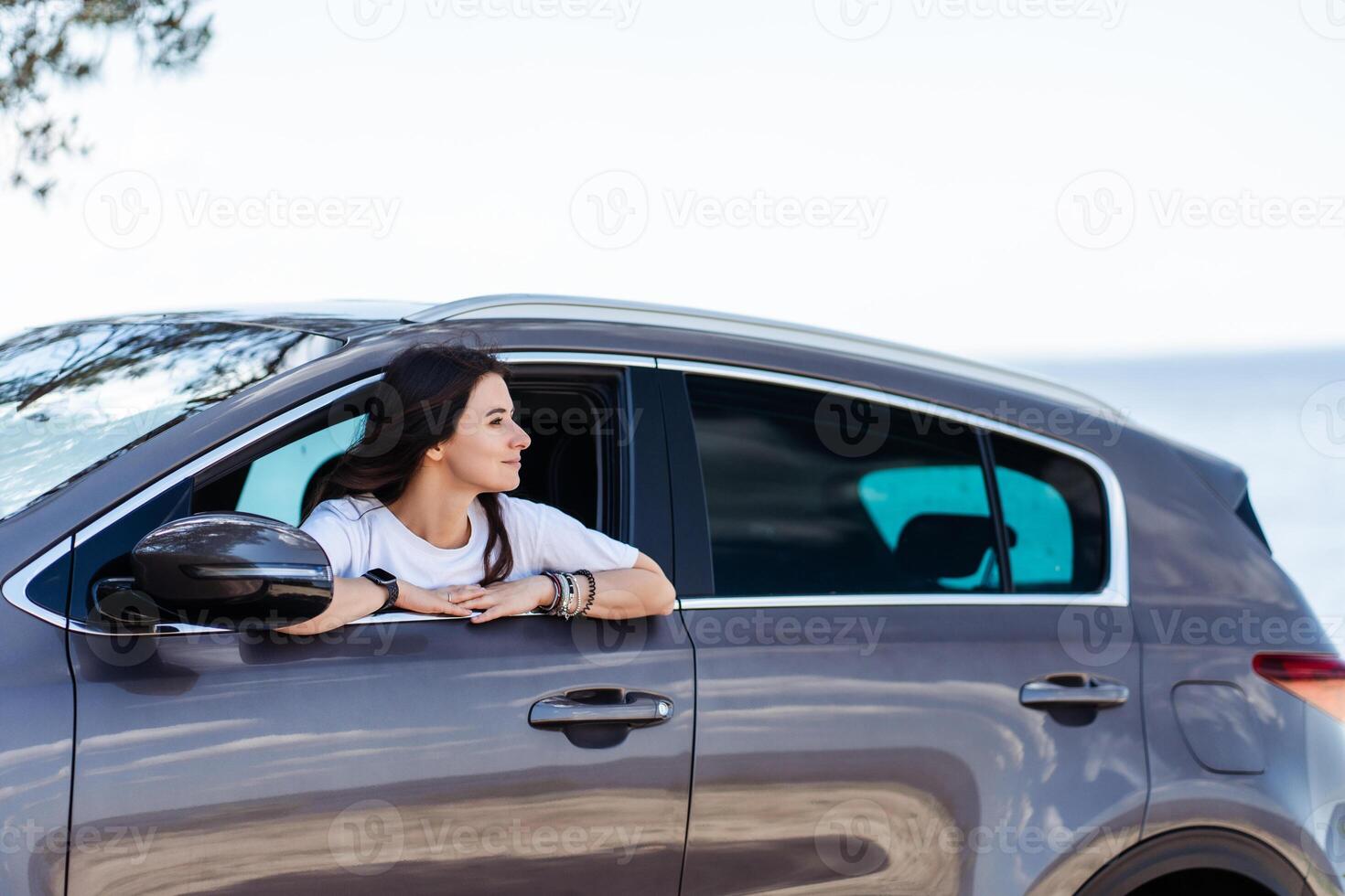 Photo of smiling woman relaxing car and looking window in summer