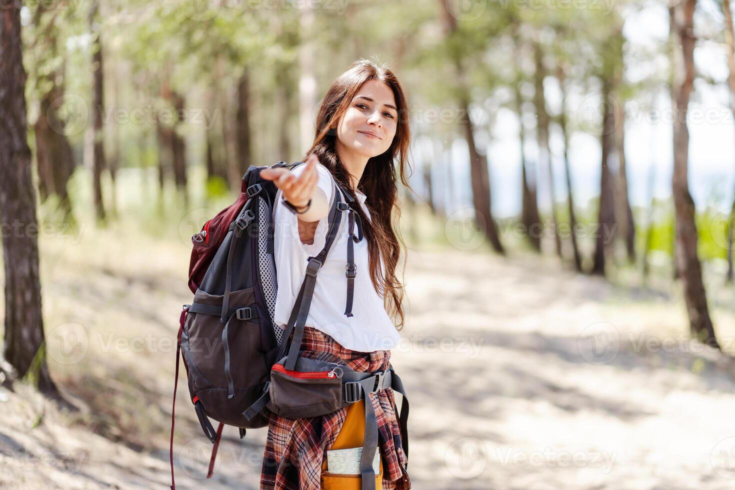 Happy smiling woman hiker looking at camera and attracting with hand photo