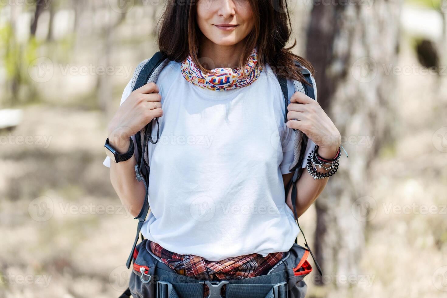 Closeup woman hiker with backpack looking at camera while hiking in forest photo