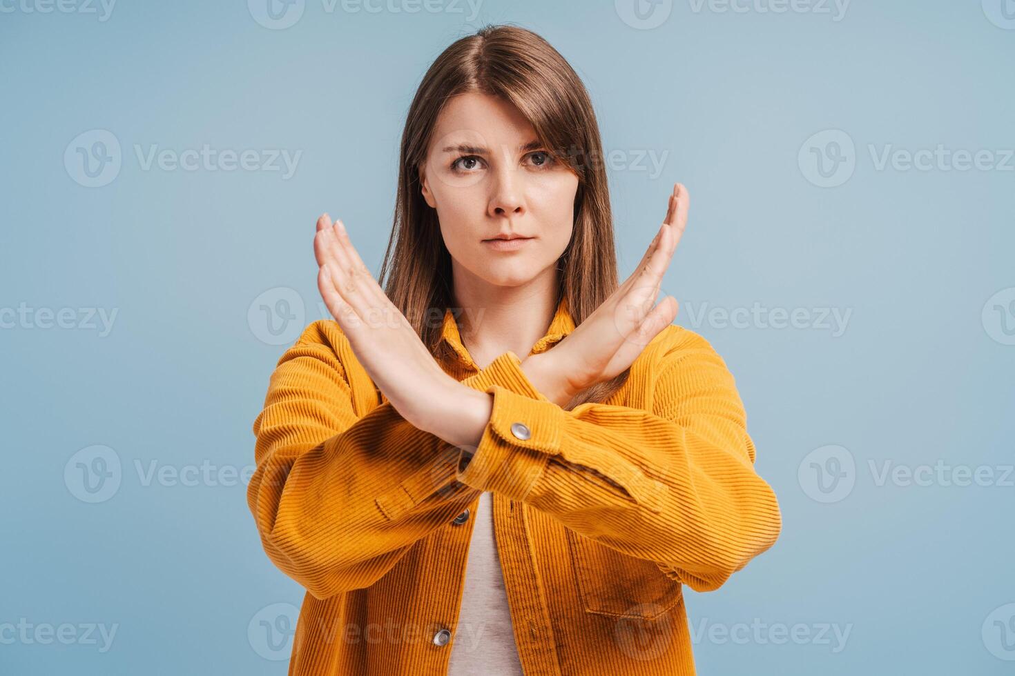 Unhappy middle aged woman showing hands stop gesture looking at camera isolated on blue background photo