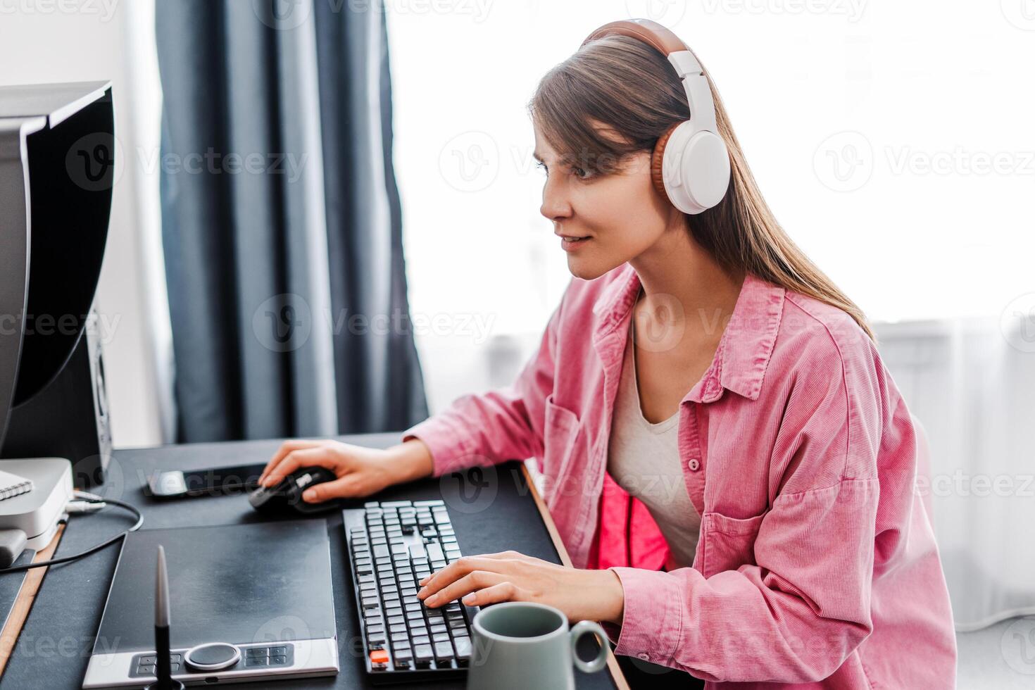 Smiling woman in headphones, gamer plying game, sitting, copywriter typing on keyboard at home photo