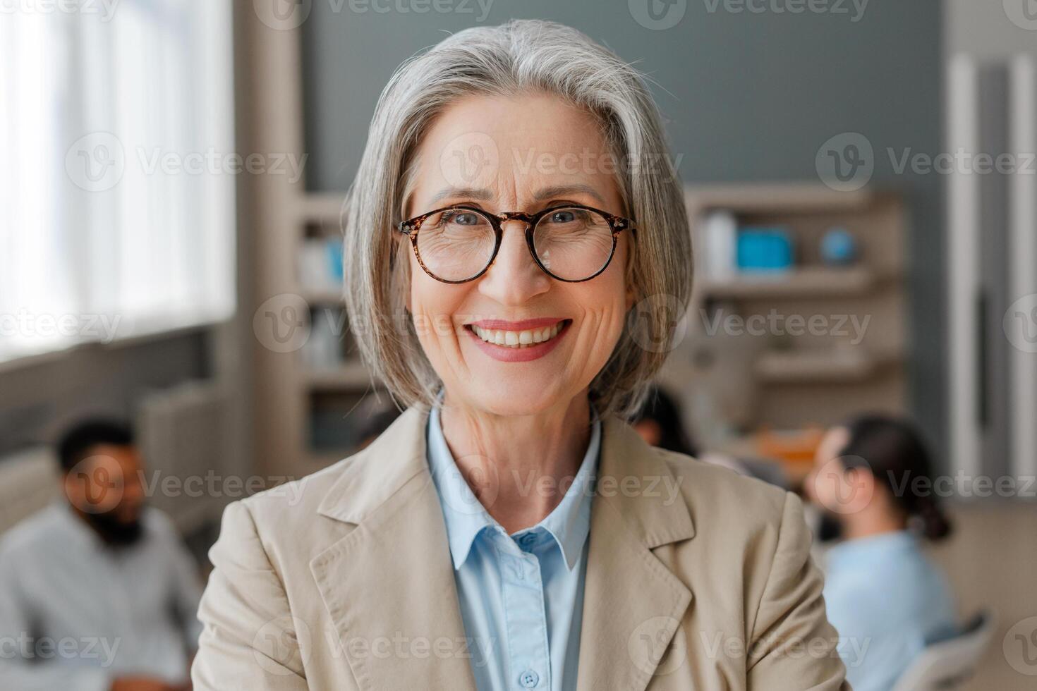 Senior businesswoman smiling in stylish eyeglasses, looking at camera posing in modern office photo