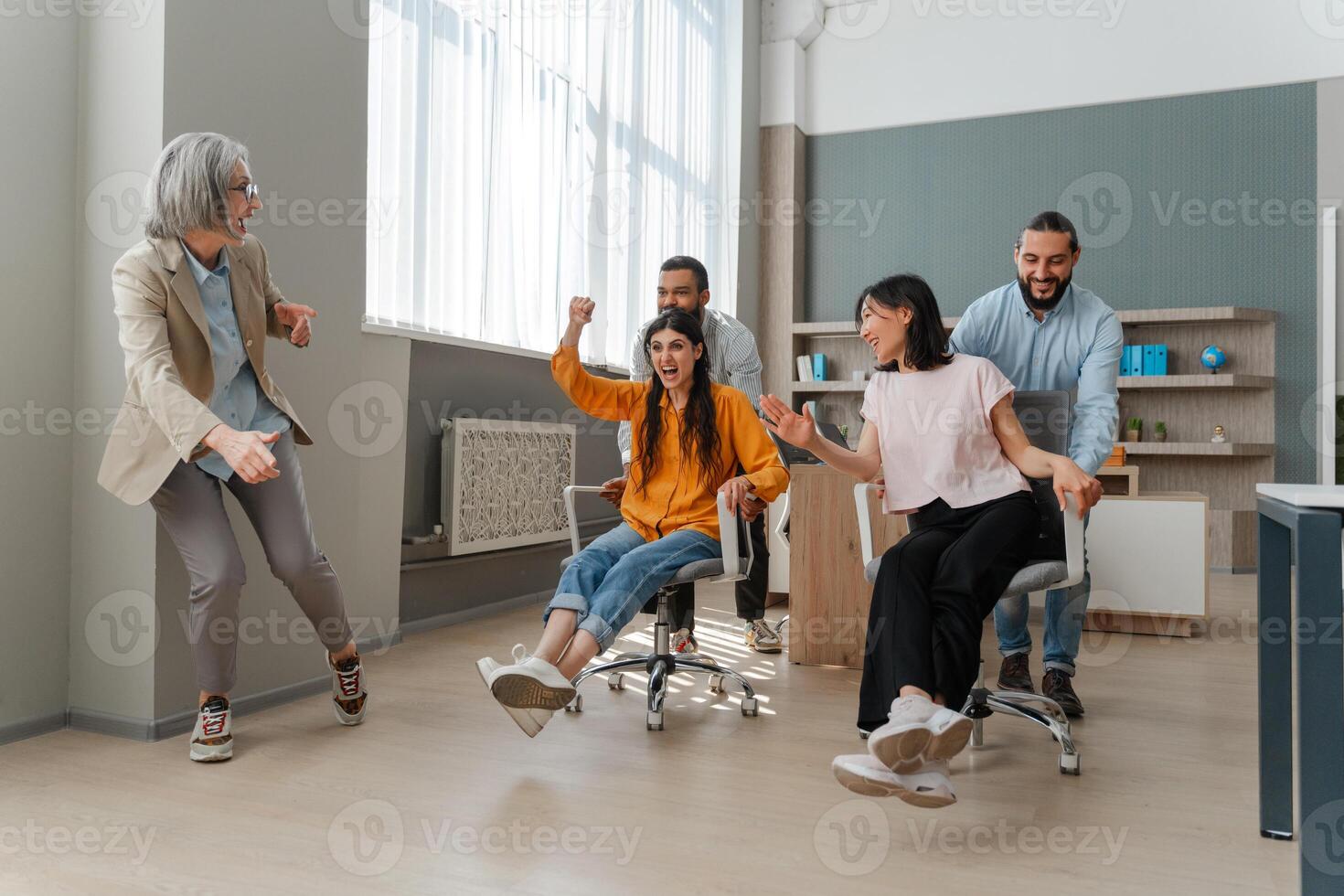 Happy business team having fun racing on chairs in office photo