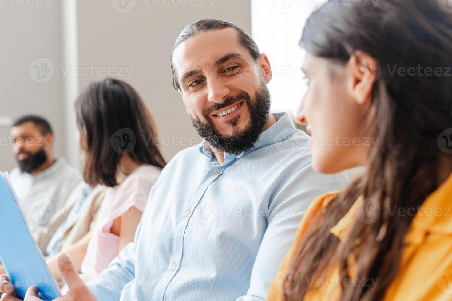 Smiling Middle Eastern bearded man talking to colleague holding a tablet photo