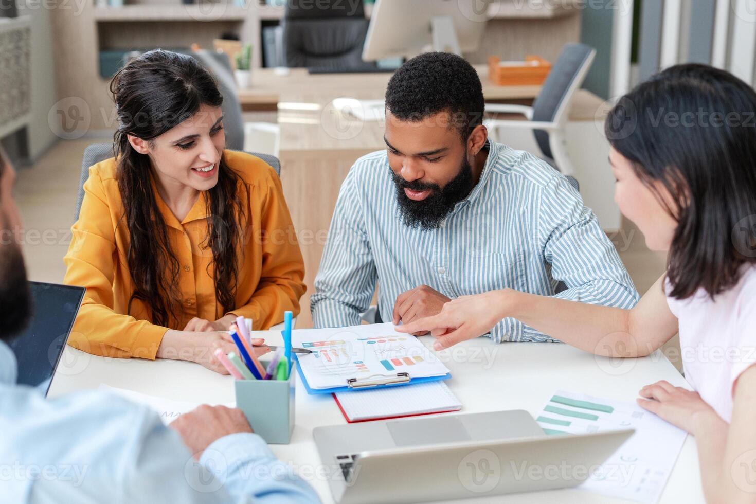 Diverse, multiethnic team of professionals analyzing charts and graphs during a productive meeting photo