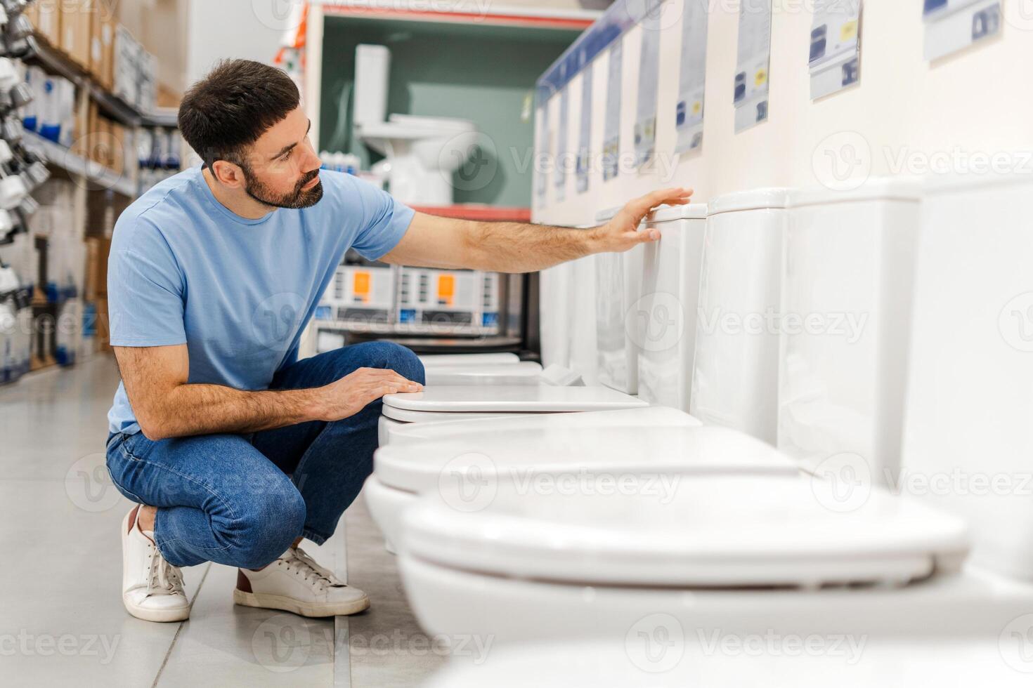 Young man looking choosing new toilet in hardware store, checking the quality photo